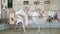 In ballet hall, girls in white ballet skirts are engaged at ballet, rehearse attitude, Young ballerinas standing on toes