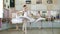In ballet hall, girls in white ballet skirts are engaged at ballet, rehearse turning, Young ballerinas standing on toes