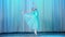 Ballet rehearsal, on the stage of the old theater hall. Young ballerina in blue ballet dress and pointe shoes, dances