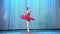 Ballet rehearsal, on the stage of the old theater hall. Young ballerina in red ballet tutu and pointe shoes, dances