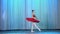 Ballet rehearsal, on the stage of the old theater hall. Young ballerina in red ballet tutu and pointe shoes, dances