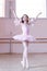 Ballet studio. Petite ballerina posing at camera