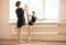 Ballet teacher adjusting leg position of young ballerinas