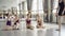 Ballet teacher experienced ballerina is dancing on tiptoes demonstrating movements to her little students sitting on