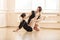 Ballet teacher showing young girl how to perform exercise on floor
