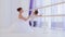 Ballet teacher is teaching little girl to stretch legs near the barre stand.
