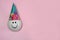 Balloon with a painted smile in a cone-shaped party hat on a pink background.