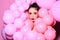 Balloon party on pink studio background. Fashion woman with many pink air balloons. Retro girl with stylish makeup and