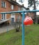 A balloon tied to a blue clothesline in front of an old house at the old yard