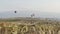 Balloons float through the sky. Tourists from around the world come to Cappadocia to tour the balloons