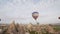 Balloons float through the sky. Tourists from around the world come to Cappadocia to tour the balloons