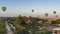 Balloons are flying over the valley. Below - cultivated fields, palm trees.