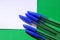 Ballpoint pens for writing on green background. View from above. The case handles white, caps blue. Handles are located in the