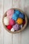 Balls of Colour Wool in Crocheted Bowl on Wooden Surface