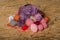 Balls of natural threads, yarn of different colors: red, purple, beige, white, gray, orange, yellow. Located on Oriented Chipboard