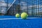 Balls next to the net and the center line of a blue paddle tennis court
