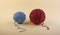 Balls of yarn in pleasant blue and burgundy colors with loose threads on a harmonious light yellow textured background.