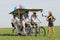 Baloons woman leading 4 guys on a quad bike on a green field sunny day