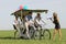 Baloons woman leading 4 guys on a quad bike on a green field sunny day