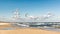 Baltic beach with distant kiteboarder on waves.