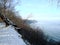Baltic sea shore in winter, steep descent to water against blue sky.