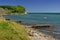 Baltic seashore with beach, anchored boat and wooded cliff