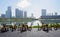 Bamboo chair and tables on blacktopped wayside in morning with modern city across lake