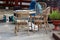 Bamboo garden furniture in shape of small table and three outdoor chairs surrounded with flowers in flower pot and children toys