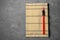 Bamboo mat with pair of red chopsticks and rest on grey table, top view. Space for text