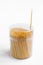 Bamboo toothpicks in plastic box with lid on white background, one toothpick taken out