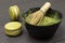 Bamboo whisk in a bowl with matcha powder. Two macaroni cakes