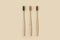 Bamboo wooden three toothbrushes on a beige background. Cleanliness and hygiene of the dental cavity. Minimalism, ecology, no wast