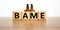 BAME symbol. Abbreviation BAME, black, asian and minority ethnic on wooden cubes. Two metalic angeles. Beautiful wooden table,