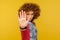 Ban, prohibition sign. Portrait of woman with curly hair holding palm up in stop gesture, warning of problems