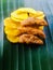 Banana chips with jaggery coated banana chips on a banana leaf.