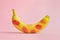 Banana covered with red lipstick marks on light pink background. Potency concept