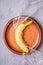 Banana fruit wrapped in stretch wrap plastic in wooden plate, stone concrete background, creative layout