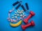 Banana, nuts, measuring tape, hand grip strengthener and dumbbells on a blue background