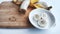 Banana with open panel on wooden board and sliced round pieces on the plate on white background. Ripe banana with peel