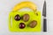 Banana, plums and kiwi, cutting board, kitchen knife on table