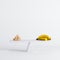 Banana sitting on seesaw with sugar cubes on white background