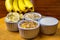 Banana sliced ramekin with oatmeal, granola and plain yogurt as side dishes under bamboo mat with bunch of bananas