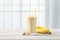 banana smoothie with oats seeds in glass on white surface