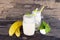 Banana smoothies juice and yellow banana fruit beverage healthy the taste yummy In glass for for milkshake on wooden background.