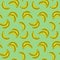 Banana vector seamless pattern; colorful bananas on green background.