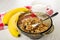 Bananas, pitcher with yogurt on napkin, spoon in brown bowl with baked muesli on wooden table