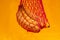 Bananas in red eco shopping string bag on yellow background. Eco friendly concept