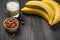 A banch of bananas with almonds and milk on wooden background.