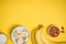 A banch of bananas and a sliced banana in a dish over yellow background.