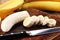 A banch of bananas and a sliced banana over a table.